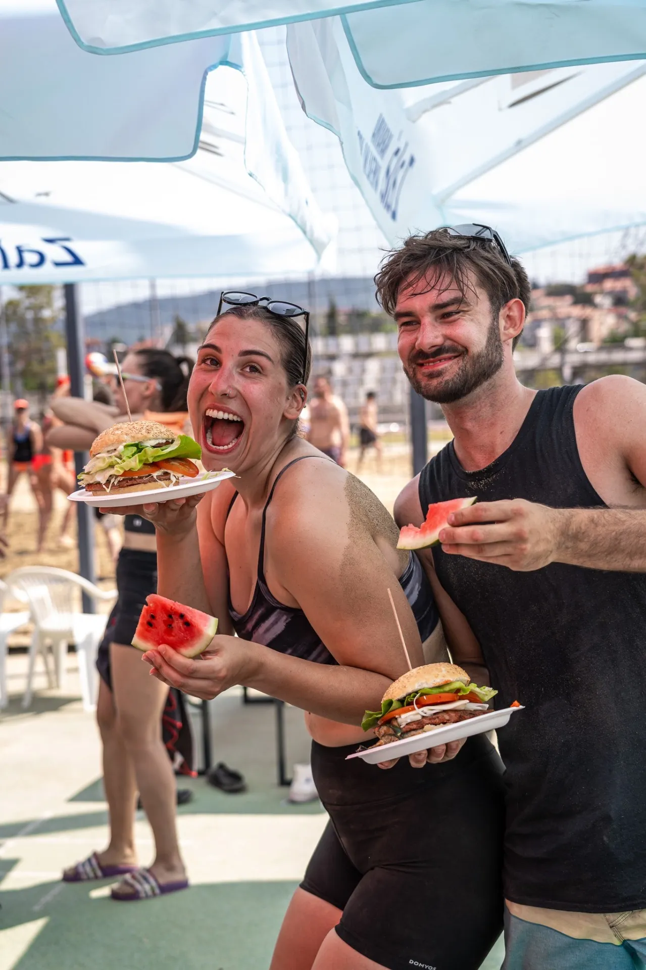 Nasmejana udeleženca turnirja uživata ob hamburgerjih in lubenici med odmorom na turnirju